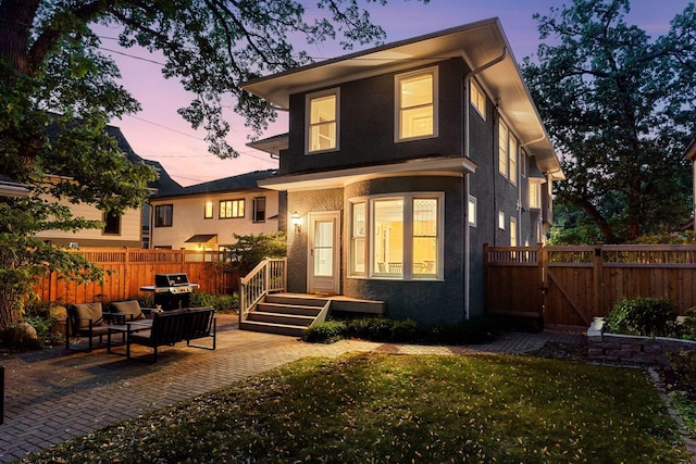 back of property with stucco siding, a gate, and a patio area