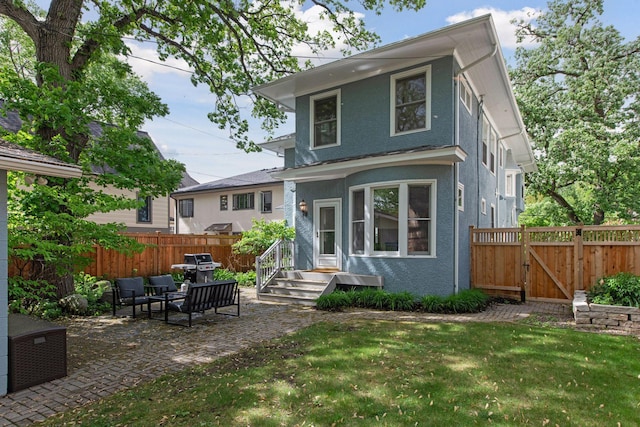 rear view of house with a patio area, a gate, and stucco siding