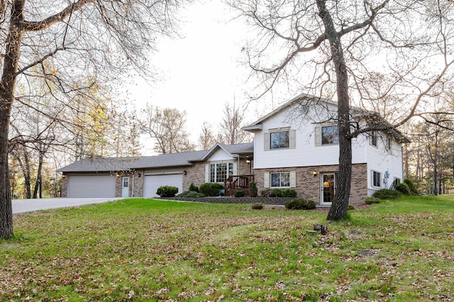 split level home featuring an attached garage, brick siding, driveway, and a front lawn