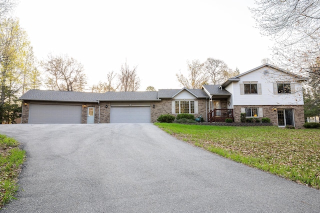 tri-level home with brick siding, asphalt driveway, a garage, and a front lawn