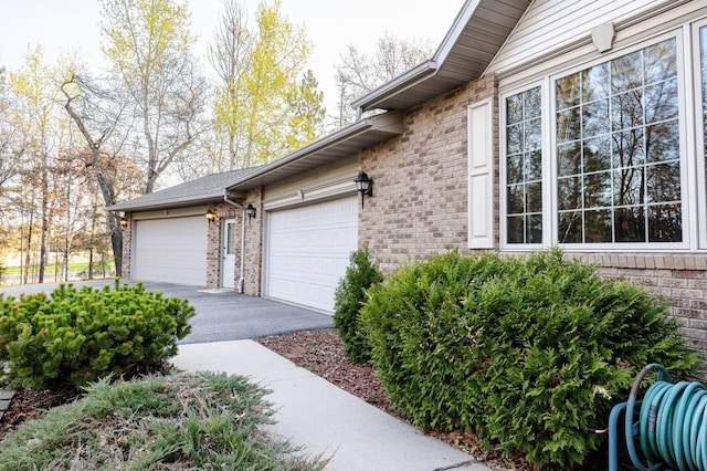 view of property exterior featuring brick siding, asphalt driveway, and an attached garage