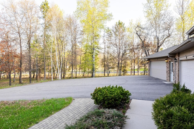 view of yard with asphalt driveway and a garage