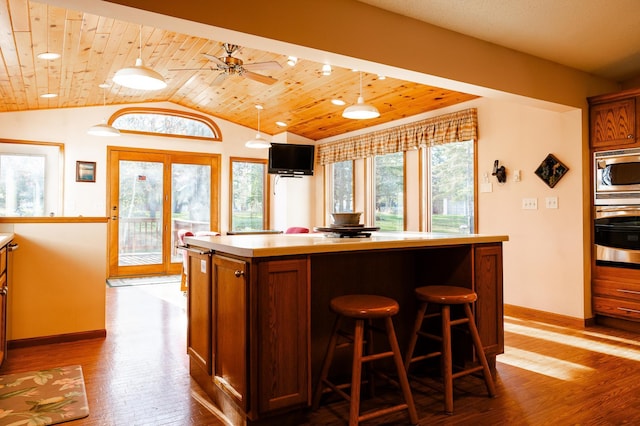 kitchen featuring appliances with stainless steel finishes, wooden ceiling, vaulted ceiling, wood finished floors, and a center island