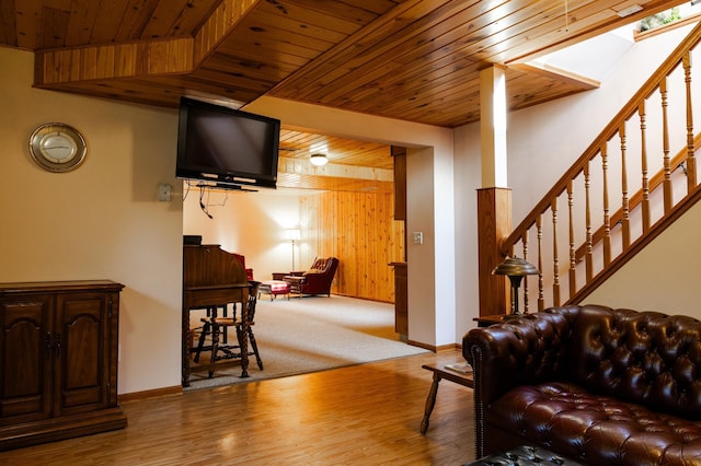 living area featuring wooden ceiling, wood finished floors, a skylight, baseboards, and wood walls