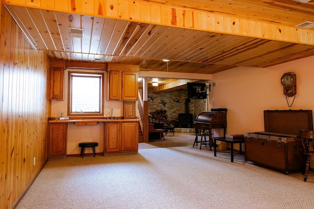 living area featuring a wood stove, light carpet, and wooden ceiling