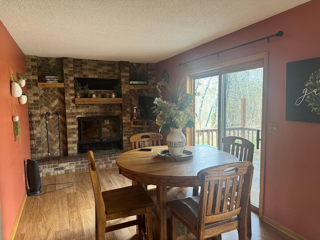 7525 Filbert Ln NE, Turtle River Twp, MN 56601 - dining room featuring a textured ceiling, wood finished floors, a fireplace, and baseboards