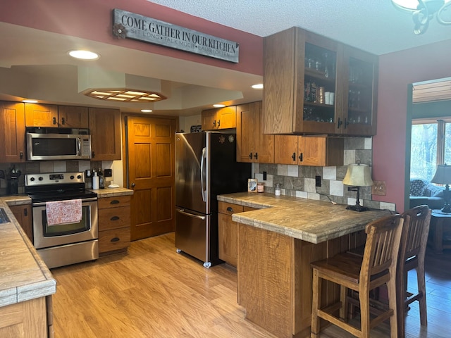 7525 Filbert Ln NE, Turtle River Twp, MN 56601 - kitchen featuring appliances with stainless steel finishes, a peninsula, glass insert cabinets, decorative backsplash, and recessed lighting