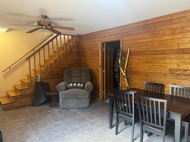 7525 Filbert Ln NE, Turtle River Twp, MN 56601 - dining room featuring a ceiling fan, a textured ceiling, stairway, and wood walls