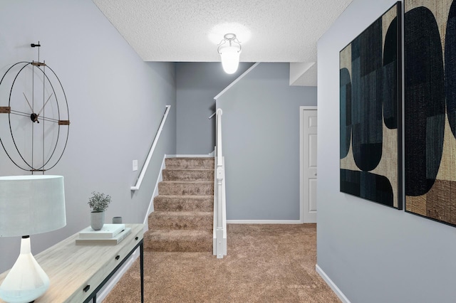 staircase featuring carpet floors, a textured ceiling, and baseboards