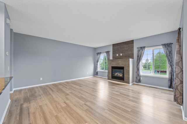 unfurnished living room featuring healthy amount of natural light, light wood-style floors, and baseboards