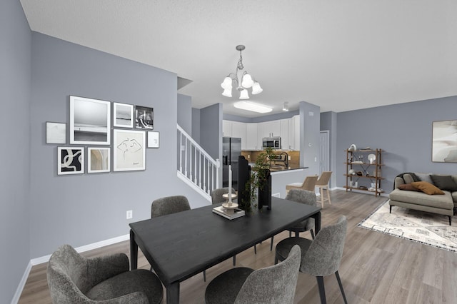 dining room featuring a chandelier, stairs, light wood-style flooring, and baseboards