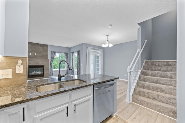 kitchen featuring dishwasher, a sink, white cabinets, light wood-style floors, and a textured ceiling