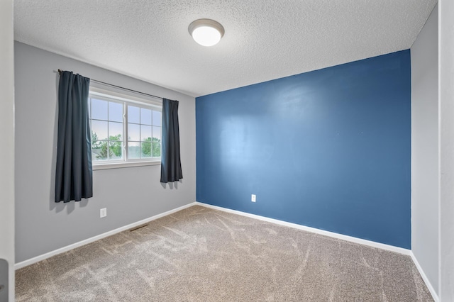 empty room with a textured ceiling, carpet flooring, and baseboards