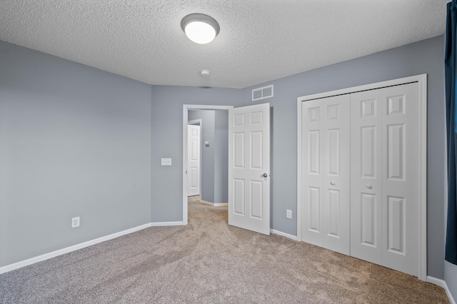 unfurnished bedroom featuring carpet, a textured ceiling, baseboards, and a closet