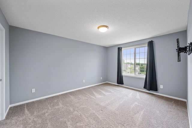 empty room with carpet floors, a textured ceiling, and baseboards