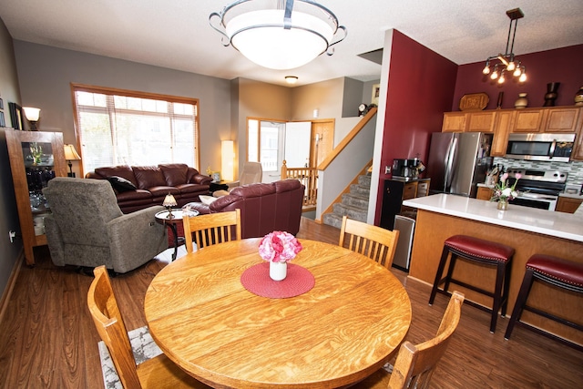 dining room featuring stairs, a chandelier, and dark wood finished floors