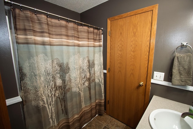 full bathroom featuring a sink, tile patterned flooring, a textured ceiling, and a shower with shower curtain