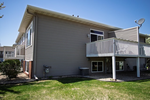 rear view of house featuring central AC unit, a yard, and a deck