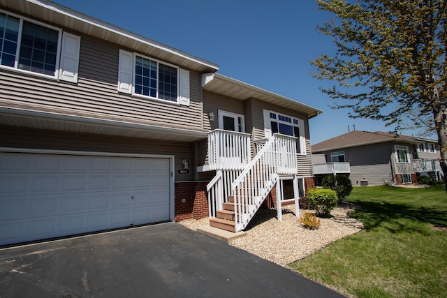 view of front of property featuring brick siding, an attached garage, a front yard, and asphalt driveway