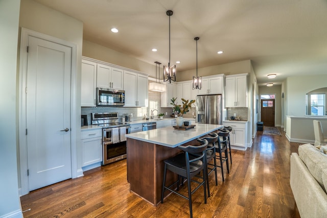 17796 Junelle Ct, Lakeville, MN 55044 - kitchen with appliances with stainless steel finishes, backsplash, a kitchen island, dark wood finished floors, and white cabinetry