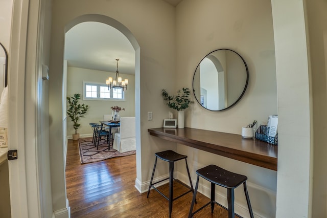 17796 Junelle Ct, Lakeville, MN 55044 - hallway featuring arched walkways, dark wood-type flooring, a chandelier, and baseboards