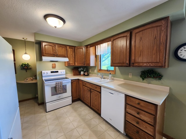 kitchen with white appliances, a sink, under cabinet range hood, brown cabinetry, and light countertops
