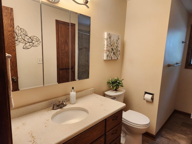 bathroom featuring toilet, vanity, and baseboards