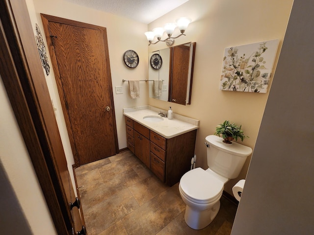 bathroom with toilet, vanity, stone finish flooring, and baseboards