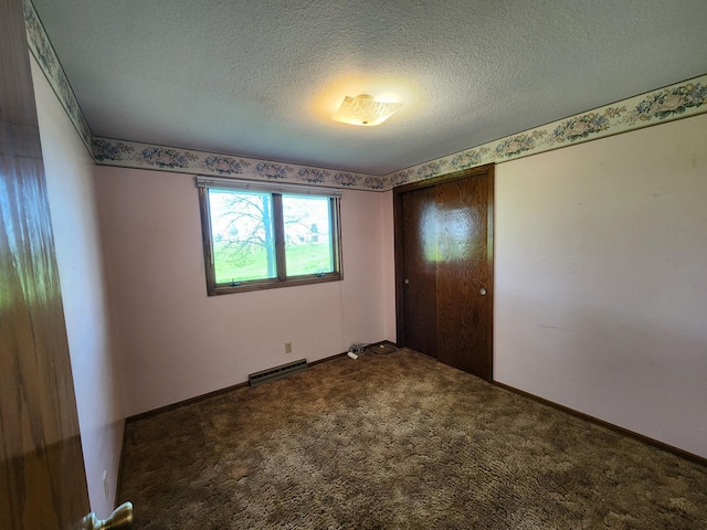 unfurnished room featuring carpet, a textured ceiling, and baseboards