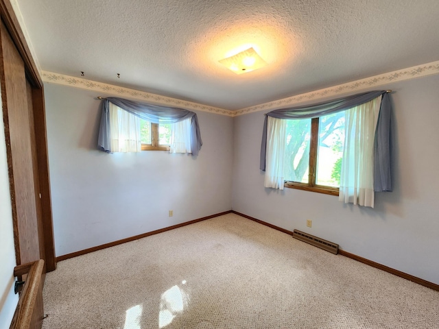 empty room with a textured ceiling, carpet floors, and baseboards