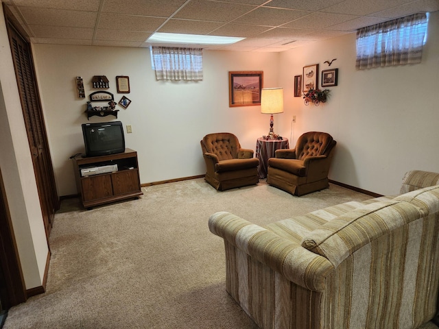carpeted living area with baseboards and a drop ceiling