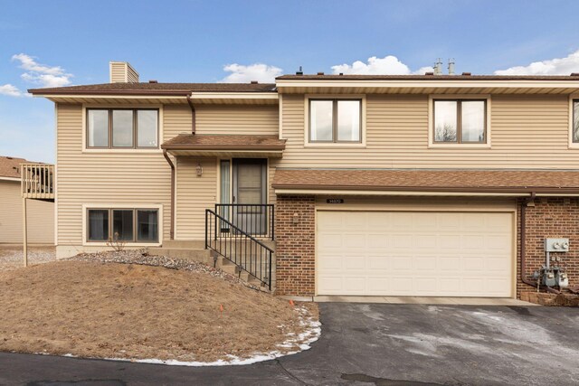 14870 Endicott Way Unit 20, Apple Valley, MN 55124 - view of front of property with a garage, asphalt driveway, brick siding, and a chimney