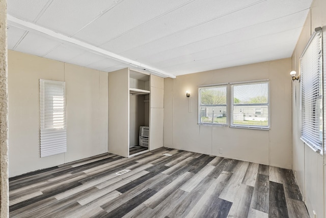 501 Forest St Unit 18, Belle Plaine, MN 56011 - unfurnished bedroom with wood finished floors, beam ceiling, and heating unit