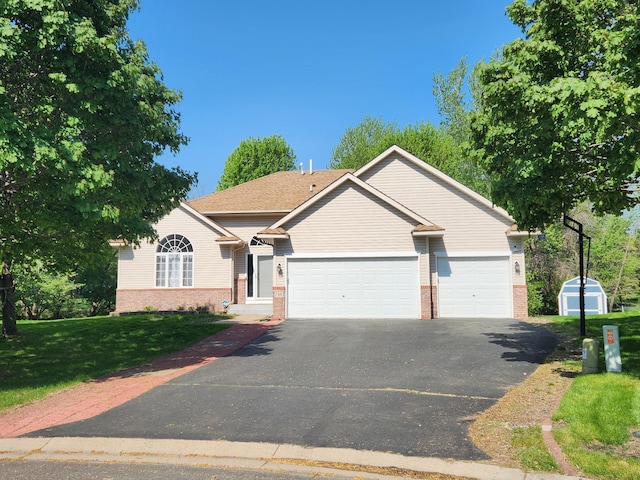 view of front of property featuring brick siding, driveway, a garage, a storage unit, and a front yard