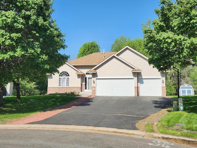 view of front of house featuring brick siding, asphalt driveway, a garage, and a front yard