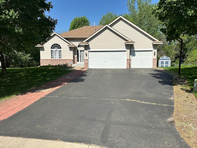 view of front facade with brick siding, driveway, a garage, a front yard, and a storage shed
