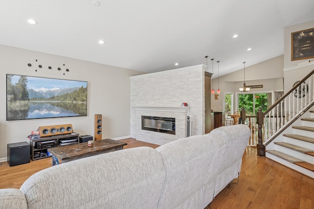 living room featuring stairs, lofted ceiling, wood finished floors, a fireplace, and recessed lighting