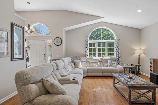living room with a chandelier, lofted ceiling, plenty of natural light, light wood-style floors, and recessed lighting