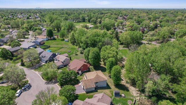 aerial view of property and surrounding area featuring nearby suburban area and a forest