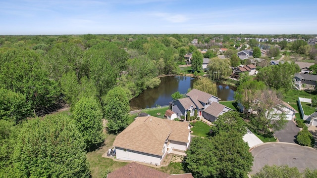 aerial view of property and surrounding area featuring a nearby body of water, a forest, and nearby suburban area
