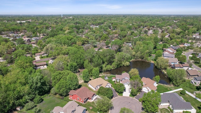 aerial view of property and surrounding area featuring a large body of water, nearby suburban area, and a forest