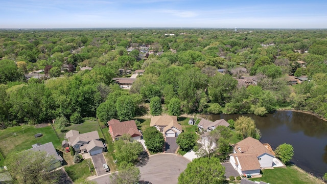 view of property location featuring a forest, a nearby body of water, and nearby suburban area