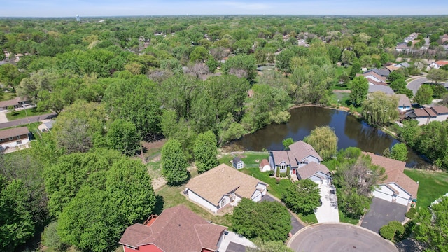 view of property location featuring a nearby body of water, a forest, and nearby suburban area