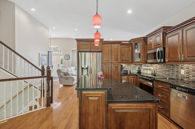 kitchen with stainless steel appliances, backsplash, light wood finished floors, a kitchen island, and recessed lighting