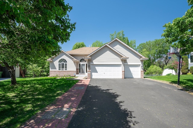 view of front of property featuring asphalt driveway, a garage, a front lawn, and brick siding
