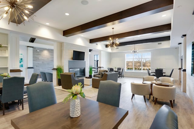 9997 Mulberry Ln, Corcoran, MN 55374 - dining space featuring a chandelier, a large fireplace, beamed ceiling, light wood-style flooring, and recessed lighting