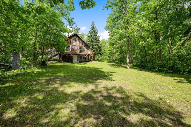 view of grassy yard featuring stairs, a deck, and a view of trees