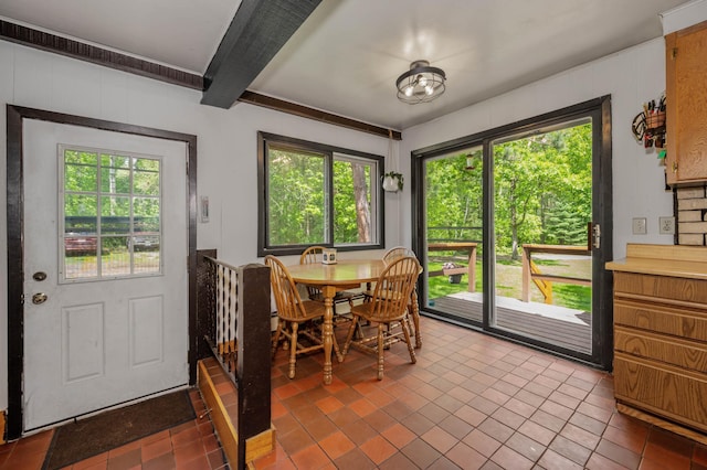 dining area with tile patterned floors, plenty of natural light, and beamed ceiling