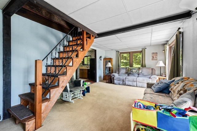 living area with carpet, stairway, and a paneled ceiling
