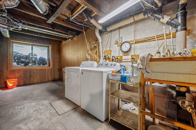 laundry area with washing machine and dryer and wooden walls